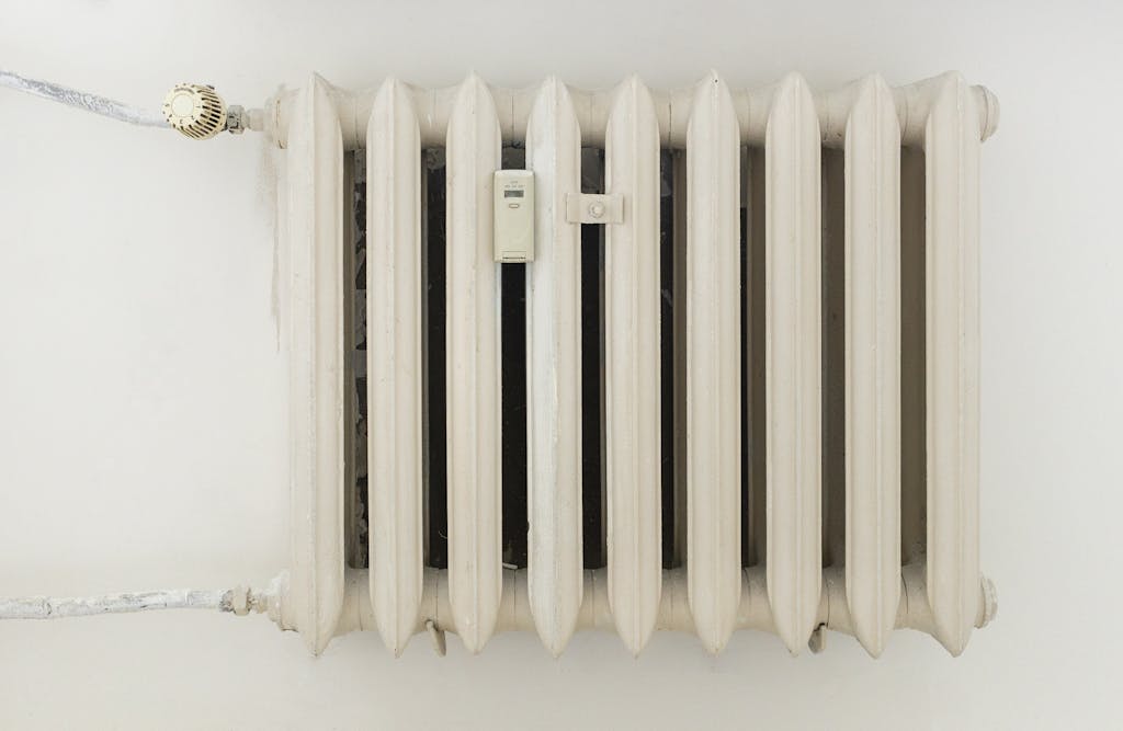 A classic white metal radiator on a plain wall, showcasing minimalist interior design.